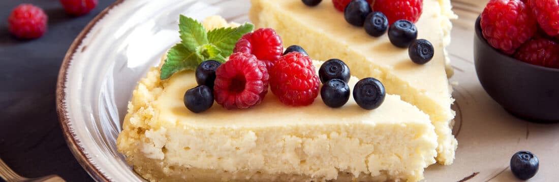 Doua felii de cheesecake facut in casa, pe farfurie in bucatarie