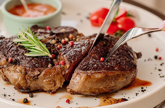 mana de femeie care taie friptura de vita in farfurie, gata de consum, pentru dieta dukan