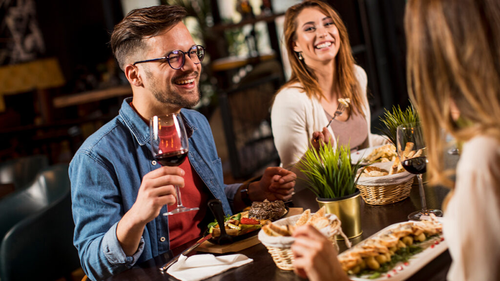 Prieteni la restaurant, rand in timp ce beau vin si mananca 