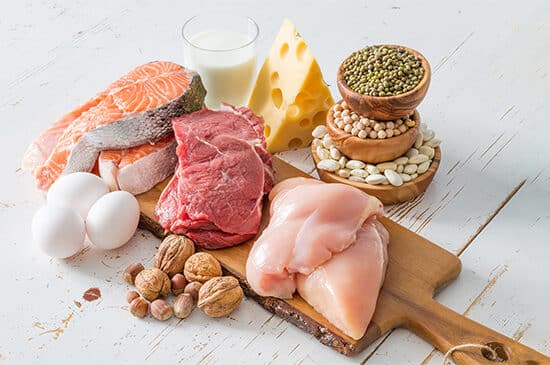 Imagine cu alimente bogate în proteine pe fundal alb: carne de pui, carne de vită, somon, ouă, brânză.