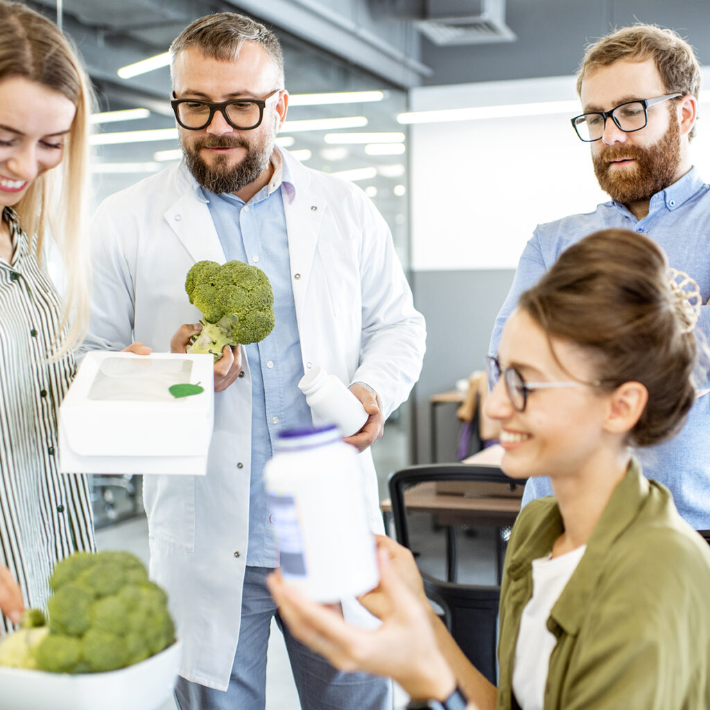 Imagine cu profesioniști, care se uită la broccoli și la suplimente.