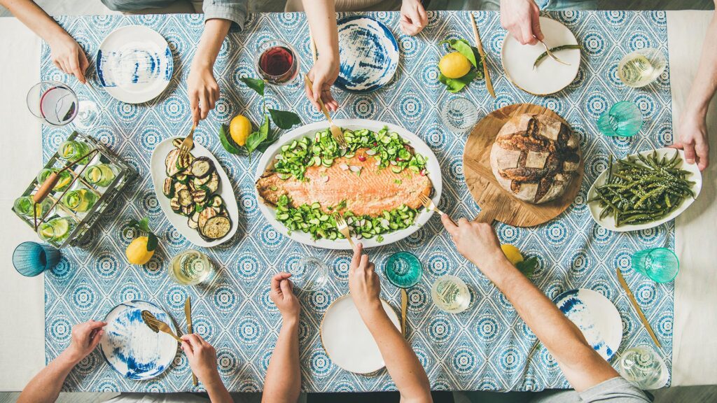 Familie la masa, impart preparate sanatoase cu legume si peste