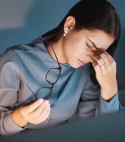 Femeie cu durere de cap in fata monitorului in casa