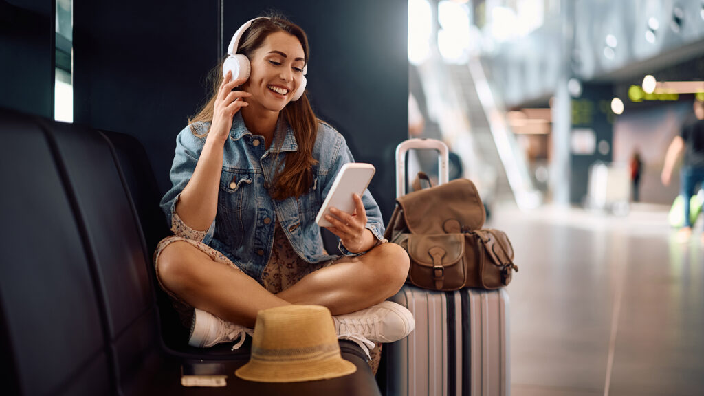 Femeie in aeroport, sta pe scaun in timp ce vorbeste la telefon