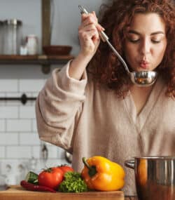 Femeie in bucatarie, pregateste supa de legume