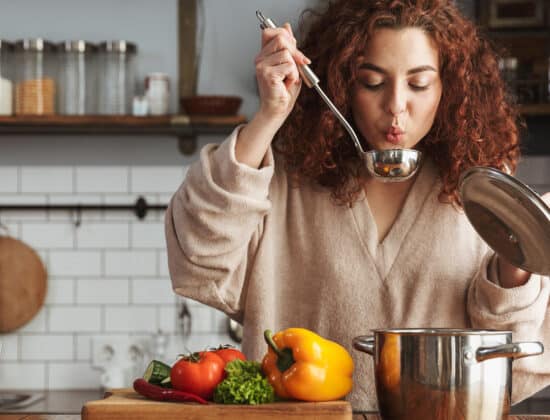 Femeie in bucatarie, pregateste supa de legume