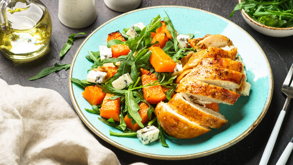 Preparat sanatos de pui cu legume, salata si branza in farfurie pe masa in bucatarie