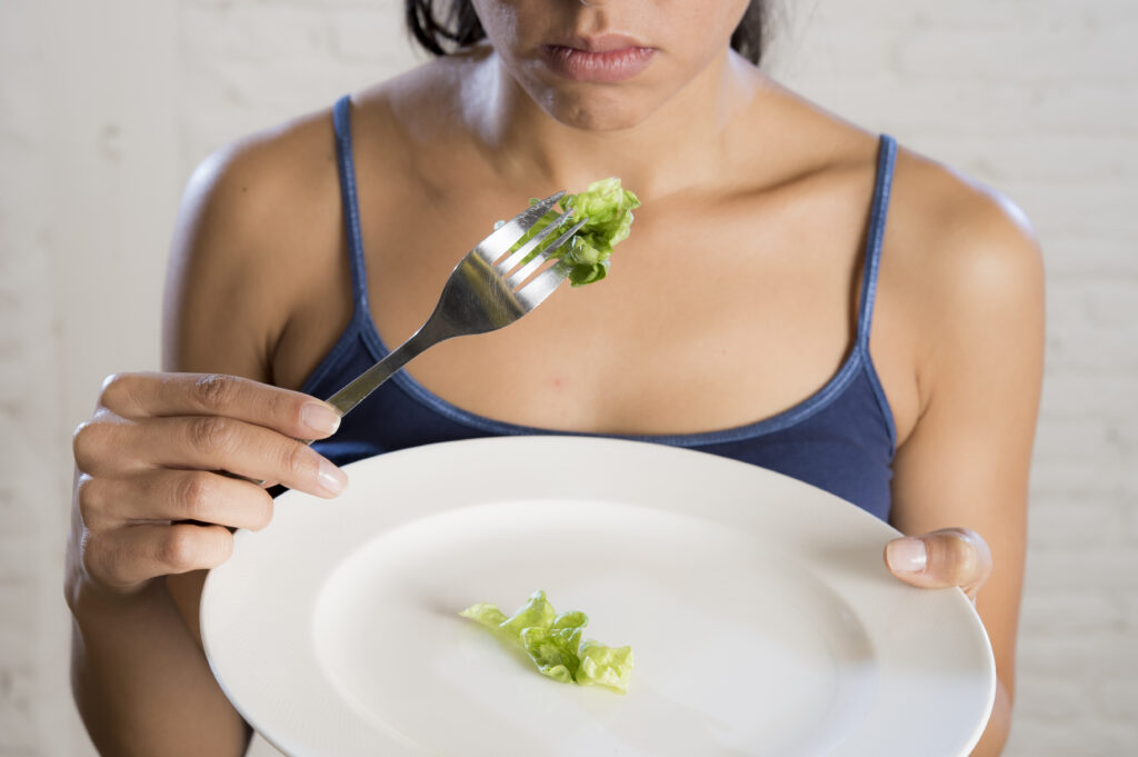 femeie mananca dintr-o farfurie aproape goala, broccoli, probleme psihice 