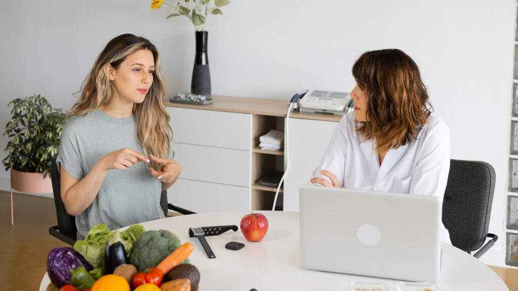 Nutritionist discuta cu pacient la masa in cabinet