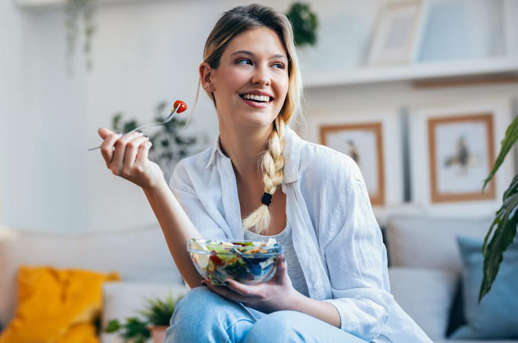 Imagine cu femeie care zâmbește în timp ce mănâncă sănătos.