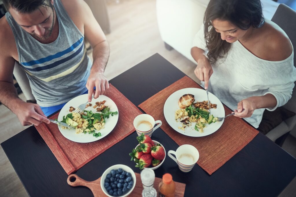 Cuplu care mănâncă împreună alimente sănătoase, bogate în vitamine.