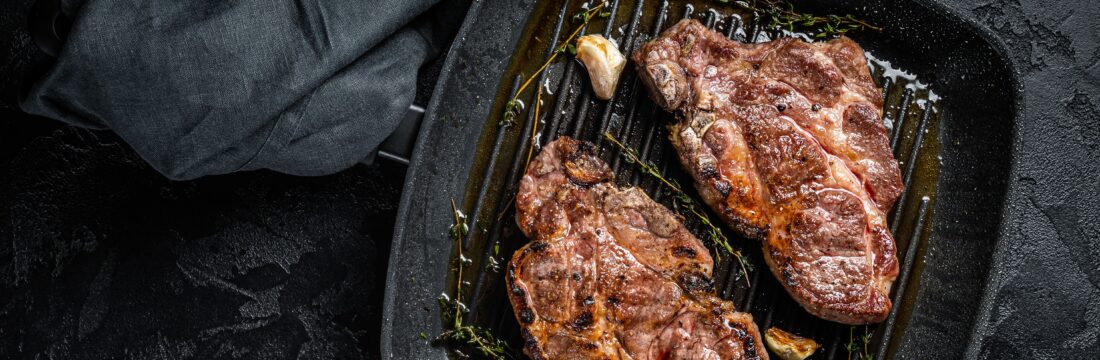 Carne de porc pe tigaie, pe fundal negru