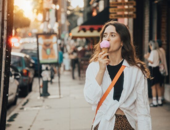femeie tanara mananca inghetata pe strada