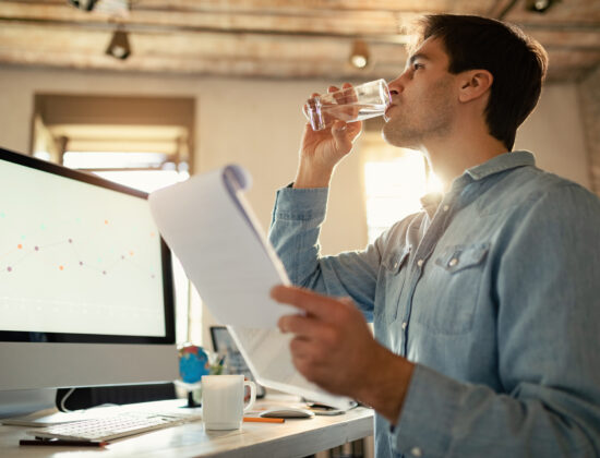Barbat care sta la birou si bea apa