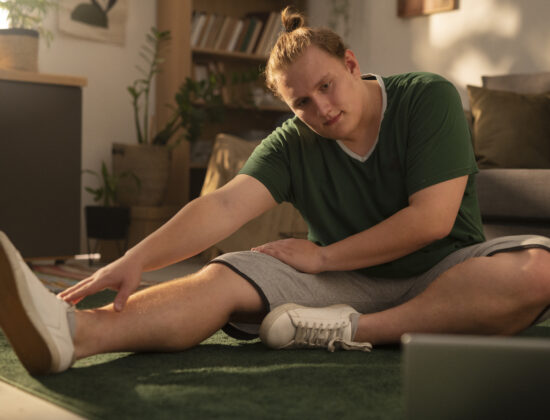 Imagine de aproape cu un baiat tanar care executa exercitii de intindere dintr-un program de sport pentru incepatori