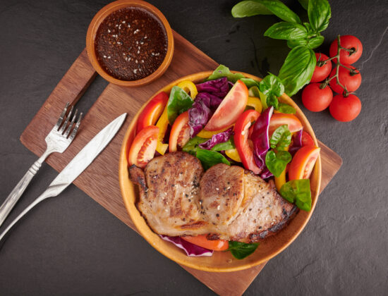 Imagine cu vedere de sus cu o farfurie cu o friptura de miel la cuptor, cu o garnitura sanatoasa langa: salata verde cu legume proaspete