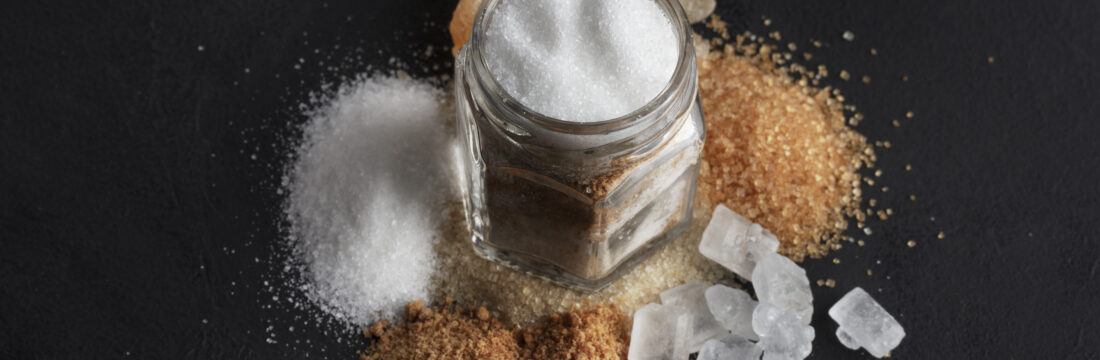 Imagine de sus cu diferite forme de aditivi alimentari intr-un borcan transparent, pe un fundal negru