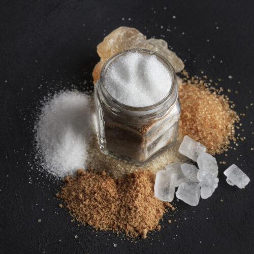 Imagine de sus cu diferite forme de aditivi alimentari intr-un borcan transparent, pe un fundal negru