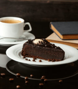 tort delicios de ciocolata pe farfurie langa o cafea
