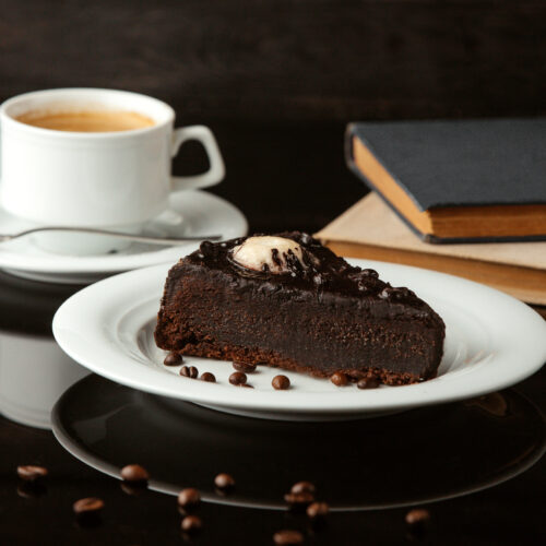 tort delicios de ciocolata pe farfurie langa o cafea