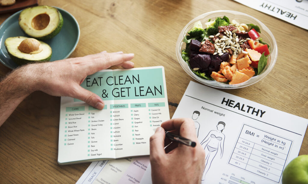 Imagine de sus cu mana unui barbat care completeaza un jurnal alimentar de slabit