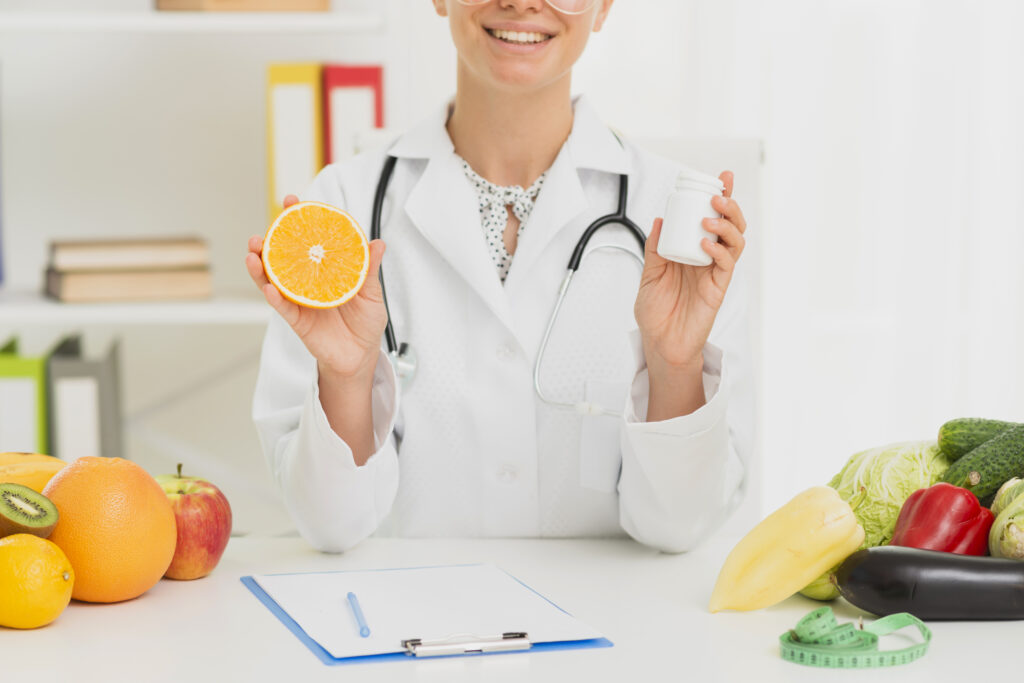Medic nutritionist care tine in mana o portocala si in cealalta un recipient cu suplimente alimentare