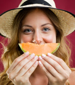 Imagine de aproape cu o femeie tanara care tine o bucata de penene galben in fata, ca un zambet