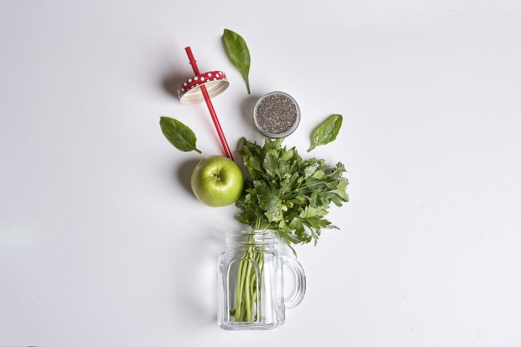 Smoothie pentru dieta detox, cu alimente vegetale verzi. Alimentele proaspete sunt asezate pe o masa alba