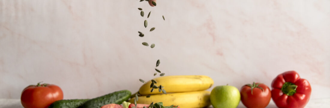 Imagine de aproape, mâna unei persoae care presară seminte peste un preparat cu alimente naturale din dieta fulger