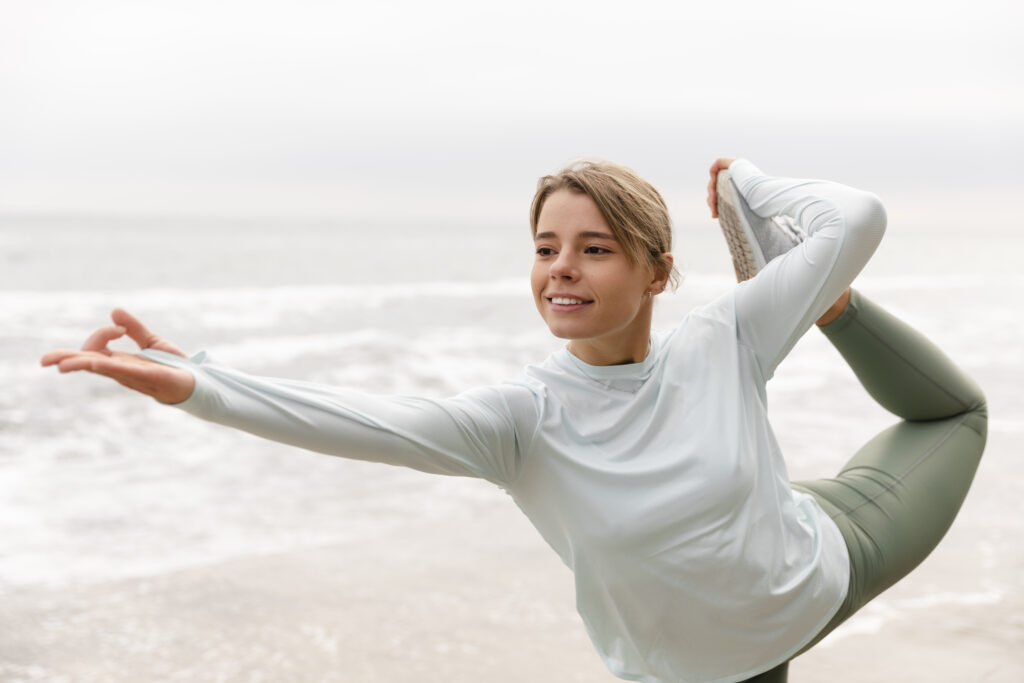 Fata tanara face exerctii de stretching afara, pe plaja