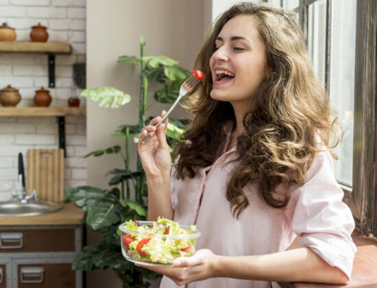 Femeie tanara mananca fericita o salata