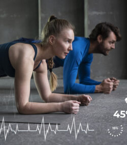un cuplu sta in plank, imbracati sport, in sala de fitness