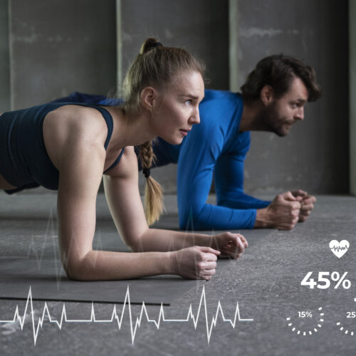 un cuplu sta in plank, imbracati sport, in sala de fitness