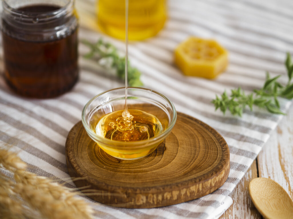 Sirop de agave turnat într-un recipent transparent, pe o masă din lemn