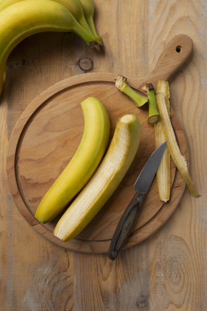 2 banane pe un tocator de lemn rotund, imagine cu privire de sus