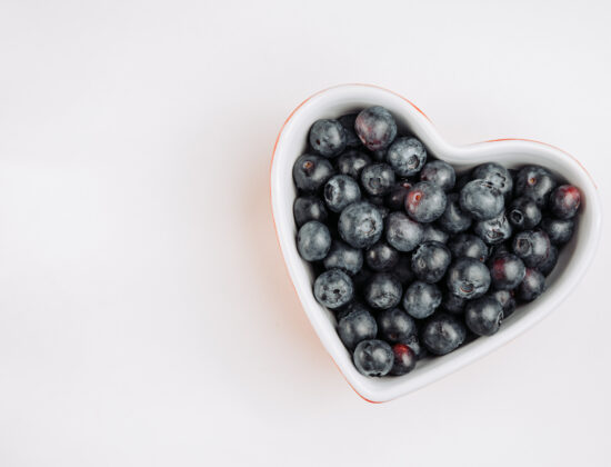 Bol in forma de inima cu afine, pe un fundal alb. Imagine de sus