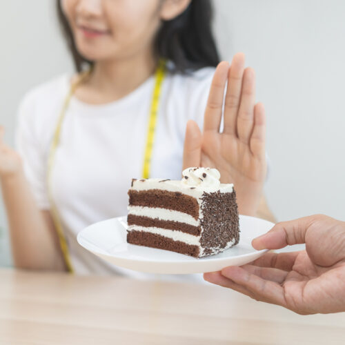 Femeie refuzând o felie de tort și preferând să mănânce un măr, pentru a-și reduce pofta de mâncare.