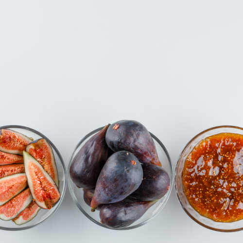 Imagine de sus, pe fundal alb: 3 borcanele transparente, unul cu smochine taiate, unul cu smochine intregi si unul cu dulceata de smochine