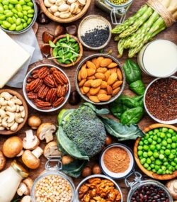 O masă plină cu legume, nuci și semințe în boluri.
