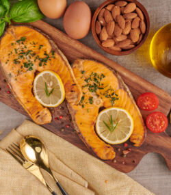Imagine cu vedere de sus cu surse naturale de omega 3, alimente proaspete cu grasimi sanatoase: somon, oua, ulei de pește, migdale