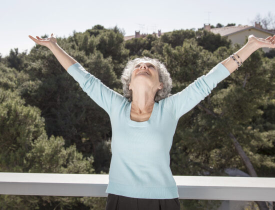Femeie fericita, sta cu mainile in aer, catre cer