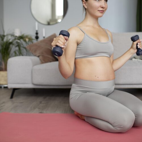Femeie insarcinata face exercitii sport usoare pentru sarcina cu greutati mici