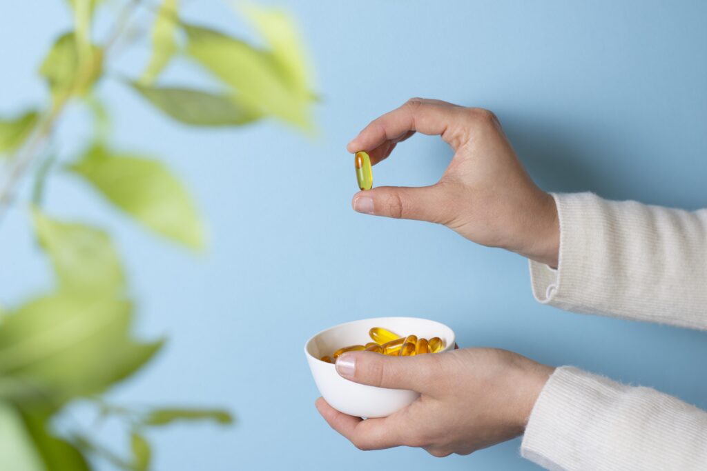 Imagine cu mana unei persoane. Arata de aproape o pastila supliment de omega-3