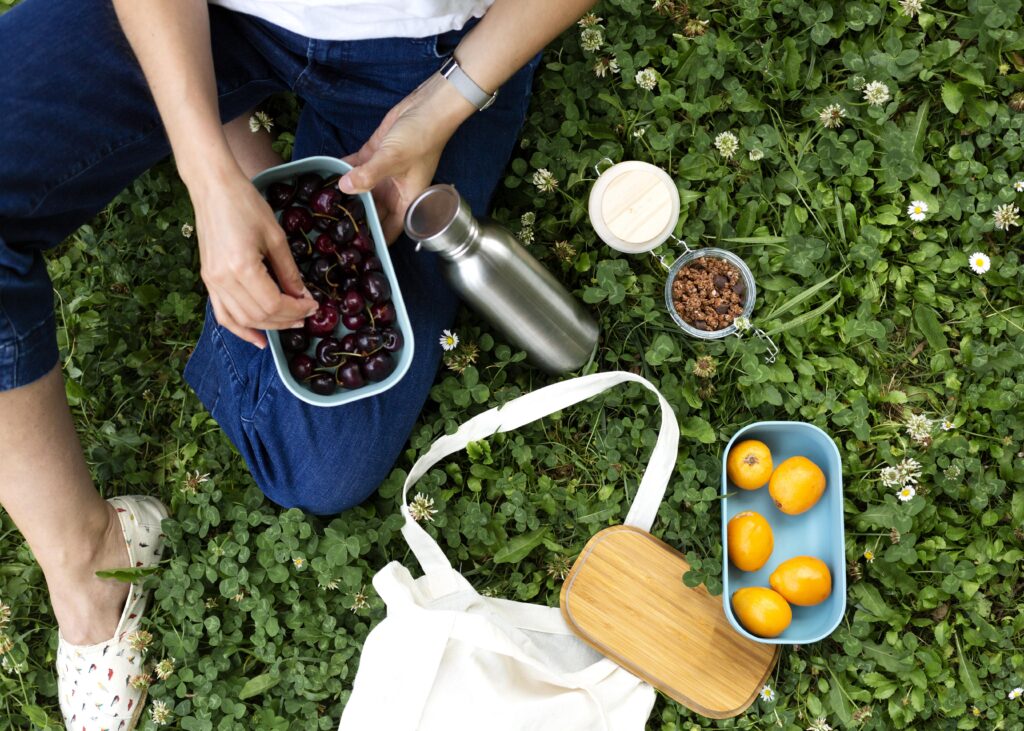 Imagine de sus. Femeie la picnic. Are caserole opace pentru alimente, deoarece protejeaza mai bine alimentele de caldura