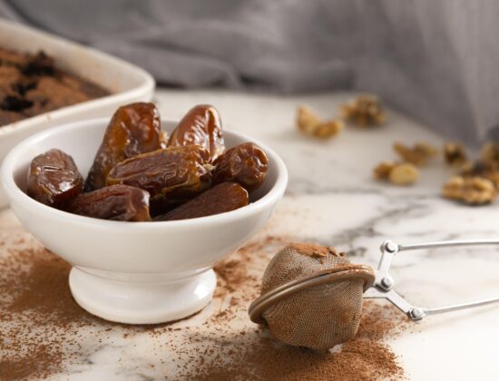 Bol alb de curmale pe un tocator de lemn, presarat cu scortisoara