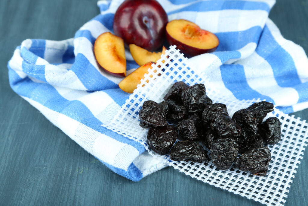 prune uscate pe masa, alaturi de prune proaspete