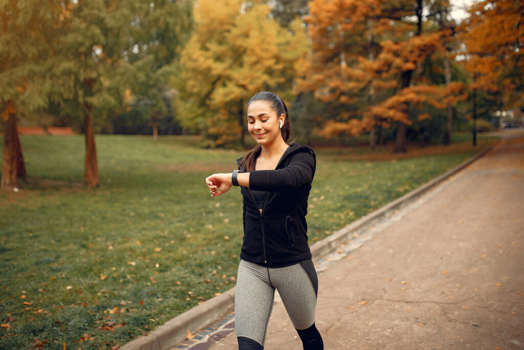 Fată tânără îmbrăcată sport face o plimbare alertă în parc pentru creșterea imunității