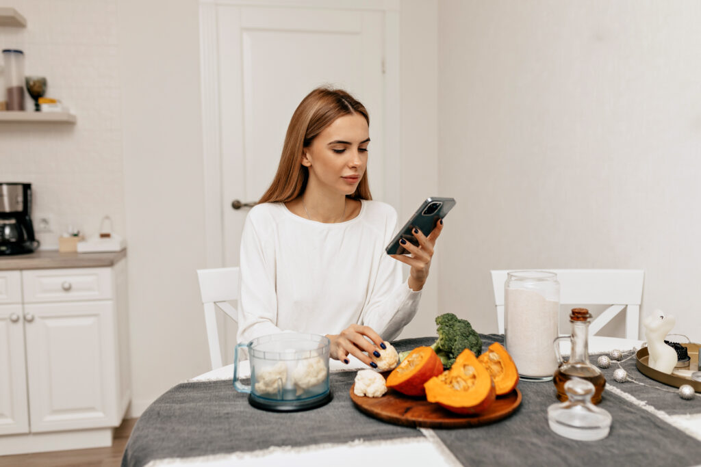 Femeie tânără caută rețete sănătoase din dieta Montignac pe telefon