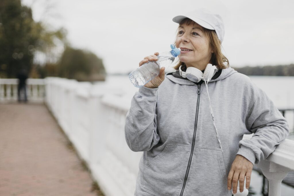 Femeie care bea apă, ia o pauză în timpul antrenamentului sport afară