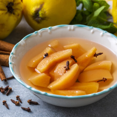 Imagine de aproape cu felii de gutui scufundate în sirop de gutui într-un bol alb